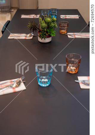 Black wooden dinning table and colorful glasses prepared for dinner 72694570