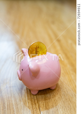 Close up photo of piggybank and bitcoin on wooden background Close up photo of piggybank and bitcoin on wooden background 72694911