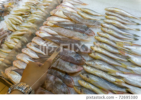 Human hand using tongs picking raw fish at seafood market Human hand using tongs picking raw fish at seafood market 72695380