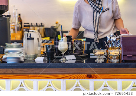 Waitress serving beverages at bar counter in Vietnamese coffee shop Waitress serving beverages at bar counter in Vietnamese coffee shop 72695438