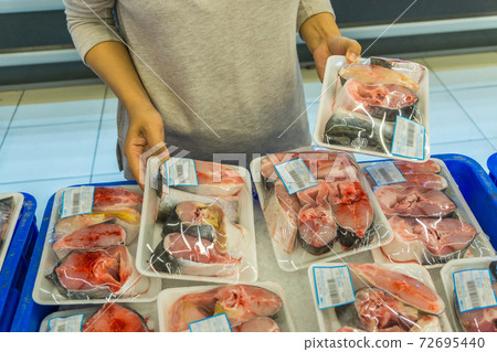 Woman buying fresh fish at seafood stall in market Woman buying fresh fish at seafood stall in market 72695440