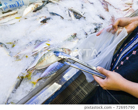 Woman hand picking fish at seafood stall in the 72695790