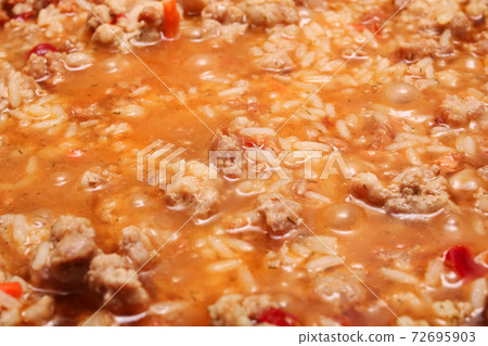 Rice and meat are cooked in a frying pan Rice and meat are cooked in a frying pan 72695903