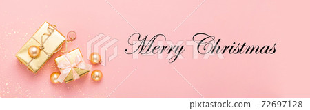 Festive boxes with satin ribbon bow golden toy balls a pastel pink background 72697128