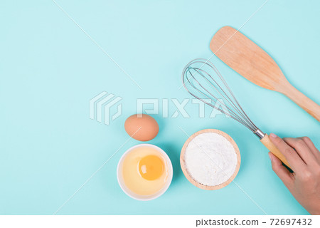 Hand holding whisk with flour and egg for bakery cooking Hand holding whisk with flour and egg for bakery cooking 72697432