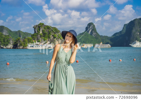 Attractive woman in a dress is traveling in Halong Bay. Vietnam. Travel to Asia, happiness emotion, summer holiday concept. Picturesque sea landscape. Ha Long Bay, Vietnam 72698096