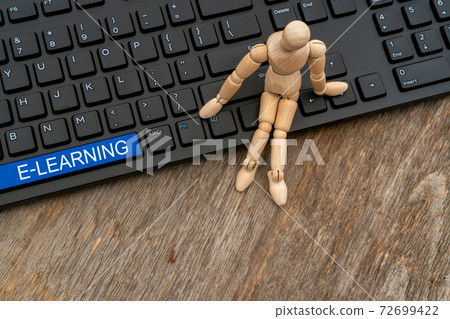 Wooden man sitting on the keyboard with E-learning 72699422