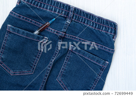 Syringe in the back pocket of blue jeans 72699449