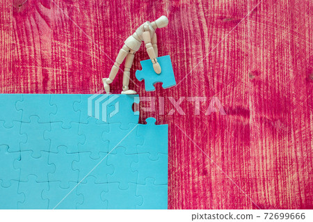 Wooden man assembling a jigsaw puzzle 72699666