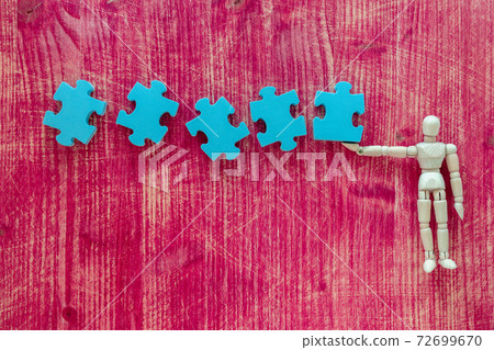 Wooden doll and pieces of blue jigsaw puzzle Wooden doll and pieces of blue jigsaw puzzle 72699670