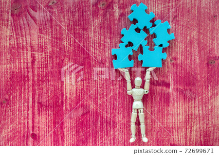 Wooden doll holding pieces of jigsaw puzzle 72699671