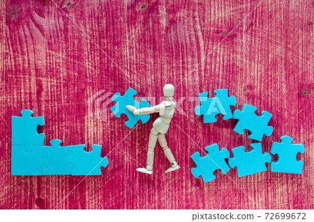Wooden man with puzzle on pink background Wooden man with puzzle on pink background 72699672