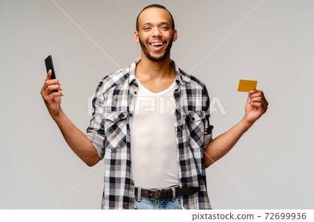 Portrait of a young african american man holding mobile cell phone and credit or discount card 72699936