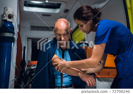 A woman in a blue uniform wraps a tourniquet around a hand of an injured man A woman in a blue uniform wraps a tourniquet around a hand of an injured man 72700240