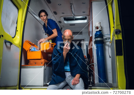 A female paramedic providing first aid to an injured man resqued from the fire 72700278