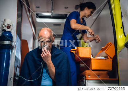 A medical worker preparing a dropping tube, a man rescued from an accident in the foreground 72700335