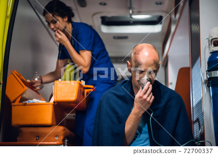 A paramedic preparing a dropping tube, a man rescued from an accident in the foreground 72700337