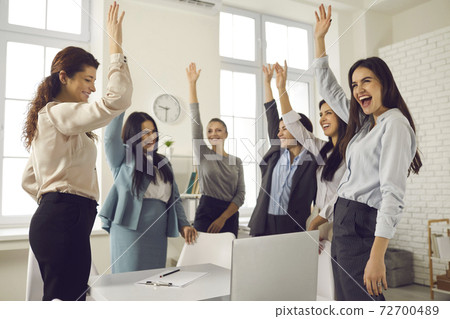Group of happy women raising hands, voting for a good idea in a corporate meeting 72700489