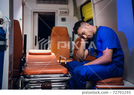 Exhausted paramedic sleeping in an ambulance car 72701293