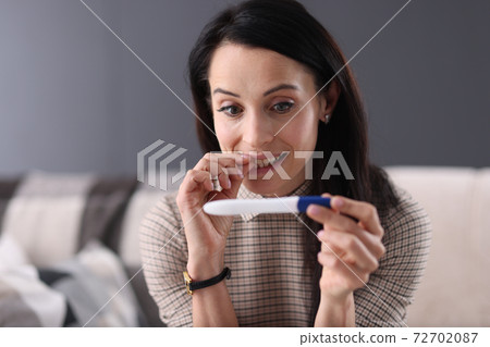 Surprised woman looking at pregnancy test closeup Surprised woman looking at pregnancy test closeup 72702087