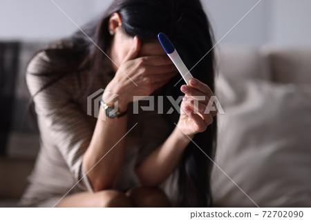 Sad woman holding pregnancy test in her hand Sad woman holding pregnancy test in her hand 72702090