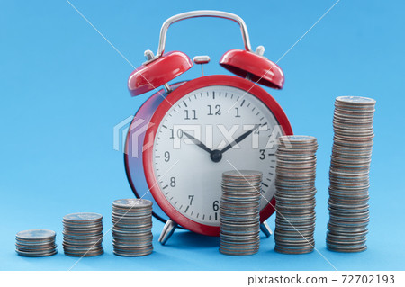 Red alarm clock and pyramid of coins 72702193