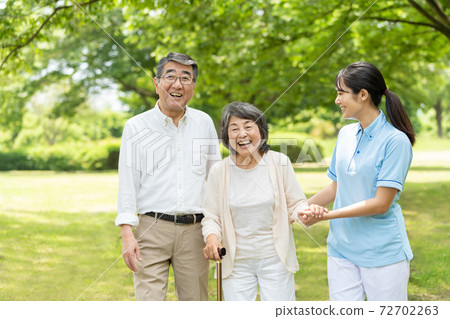 Senior couple walking in the park and care givers Senior couple walking in the park and care givers 72702263