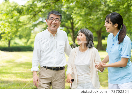 Senior couple walking in the park and care givers 72702264