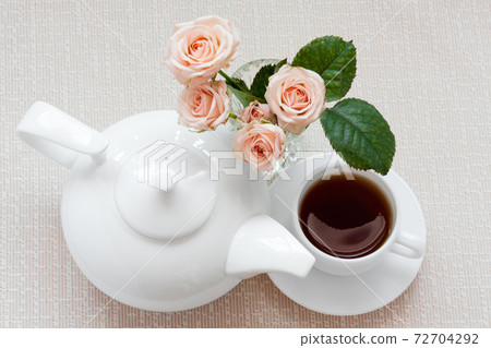 teapot, cup, and roses on a plate 72704292