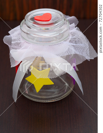 empty jar with a bow on a wooden background 72704302