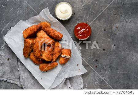 Homemade chicken nuggets. Nuggets on white parchment. Ketchup and mayonnaise. Copyspace. Gray background. Top view. 72704543