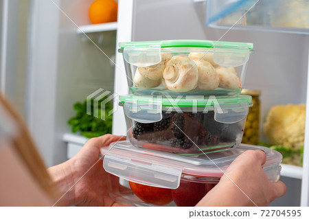Female hands taking storage box with food from a fridge Female hands taking storage box with food from a fridge 72704595