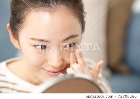 Young woman putting in contact lenses 72706166