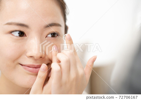 Young woman putting in contact lenses Young woman putting in contact lenses 72706167