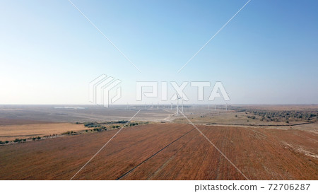 Windmills near the field. Top view from a drone. 72706287