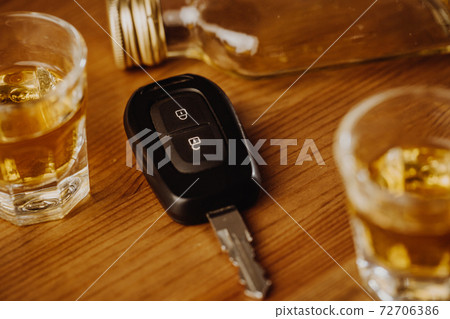 Close up of a car keys and very strong alcohol on the table, do not drink and drive concept Close up of a car keys and very strong alcohol on the table, do not drink and drive concept 72706386