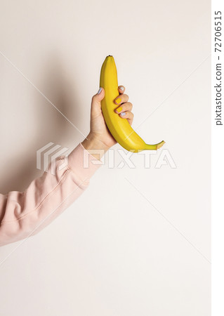 Hand with yellow and gray manicure holds a banana 72706515
