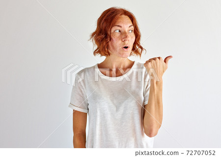surprised young woman pointing finger at side, right surprised young woman pointing finger at side, right 72707052