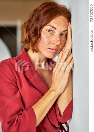 calm sleepy redhead woman leaned on wall in studio 72707099