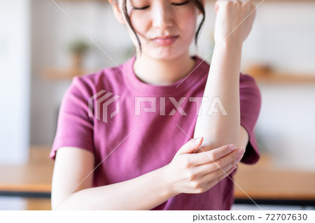 A young woman looking at her elbows A young woman looking at her elbows 72707630