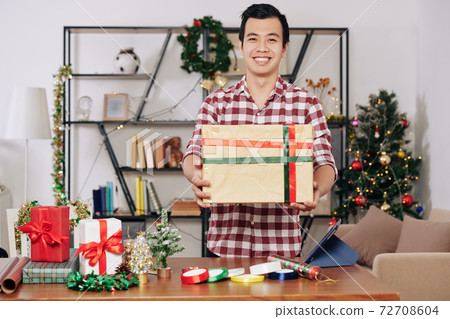 Man holding wrapped Christmas present Man holding wrapped Christmas present 72708604