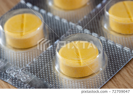 A yellow tablets in blister pack, close up. A yellow tablets in blister pack, close up. 72709047