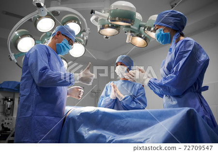 Medical team standing beside patient after successful surgery. 72709547