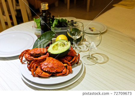 Close-up boiled red crabs, avocado, laurel, wine glasses, olive oil, lettuce 72709673