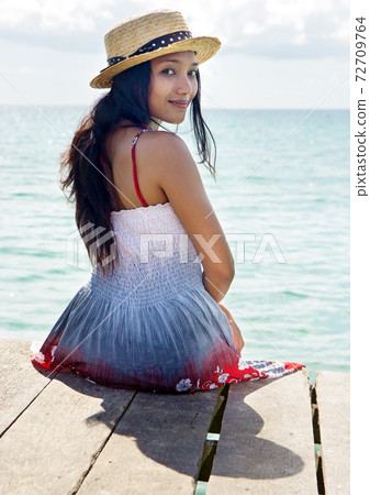 young woman in dress sitting by the sea young woman in dress sitting by the sea 72709764