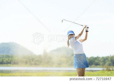 Golfer woman chip golf ball out of a sand trap. 72710847