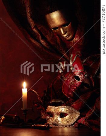 Carnival masks, dice and small brass candlestick with burning candle. Carnival masks, dice and small brass candlestick with burning candle. 72710875