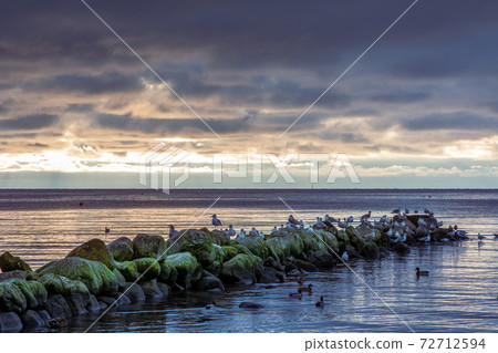 A beautiful sunset over the green boulders on a wave breaker. Photo from Hallevik, Blekinge, Sweden 72712594