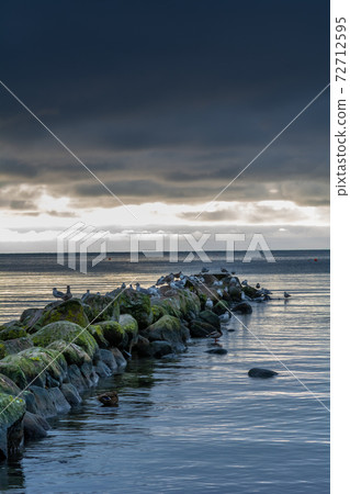 A beautiful sunset over the green boulders on a wave breaker. Photo from Hallevik, Blekinge, Sweden 72712595