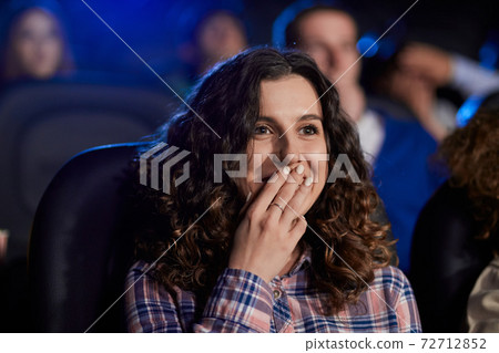 Young laughing girl watching comedy in movie theater. Young laughing girl watching comedy in movie theater. 72712852